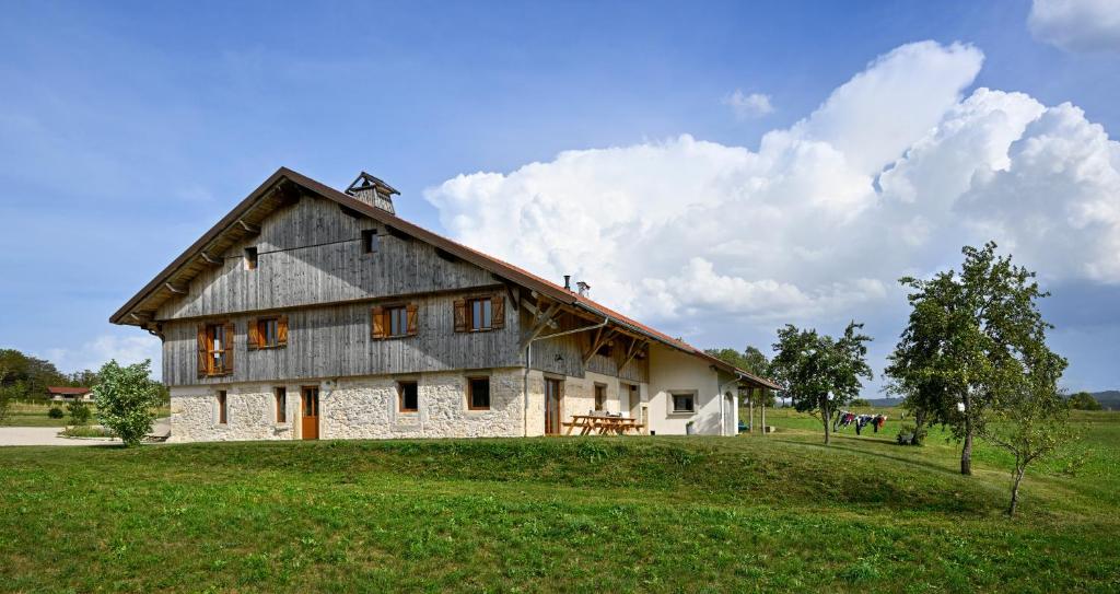 une grande maison au sommet d'une colline herbeuse dans l'établissement Bienvenue Au Grand Cœur Chaux, à Guyans-Vennes