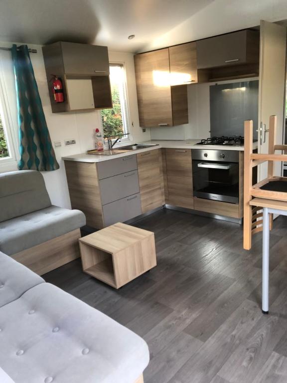 a kitchen with wooden cabinets and a stove top oven at Mobil'home - Camping **** Les Charmettes in Les Mathes