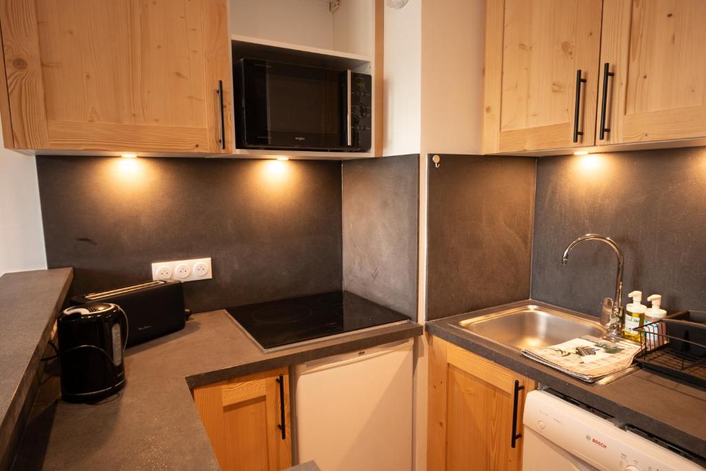 une cuisine avec un évier et un micro-ondes dans l'établissement Tignes - Beau studio pied pistes, à Tignes