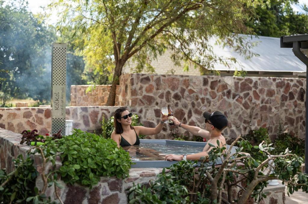 Summerplace Game Reserve في فالووتر: كانتا جالستين في حوض استحمام ساخن مع كوب من النبيذ