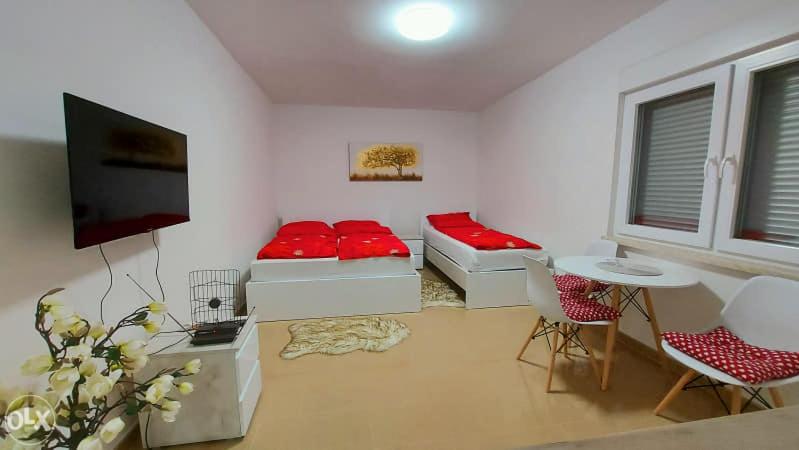 a living room with red pillows and a flat screen tv at Apartmani BORSALINO in Tuzla