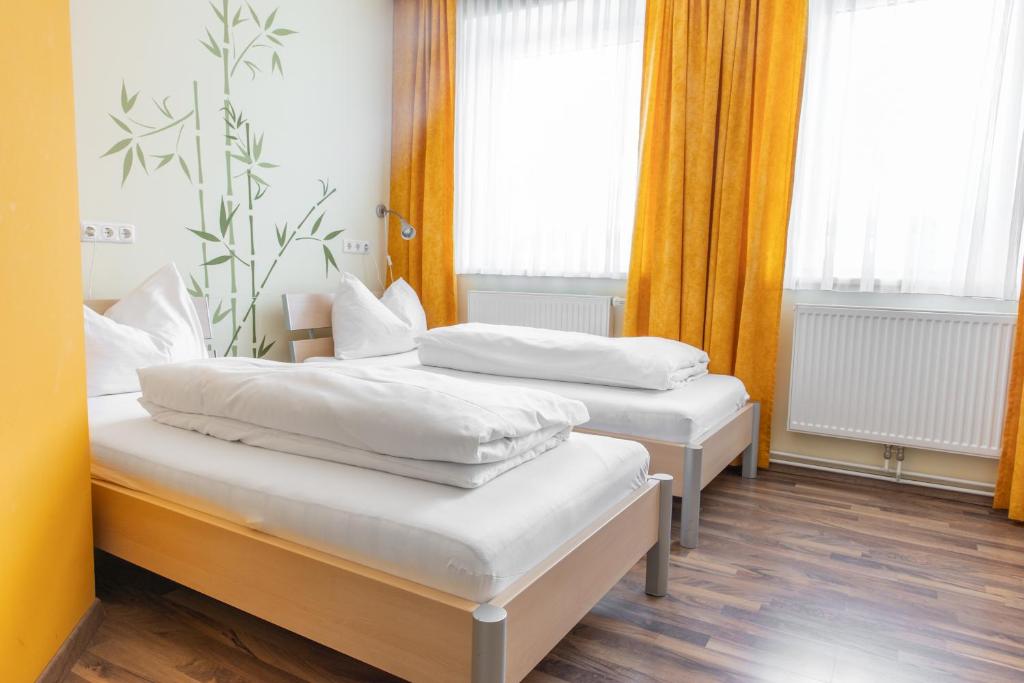 2 Betten in einem Zimmer mit gelben Vorhängen und Fenstern in der Unterkunft Wohlfühlwelt Riegler in Allentsteig