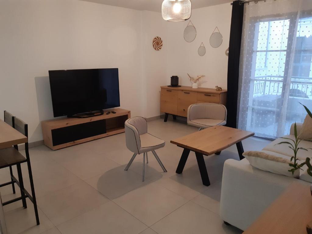 un soggiorno con TV, tavolo e sedie di Appartement Proche du Port de Bonifacio a Bonifacio