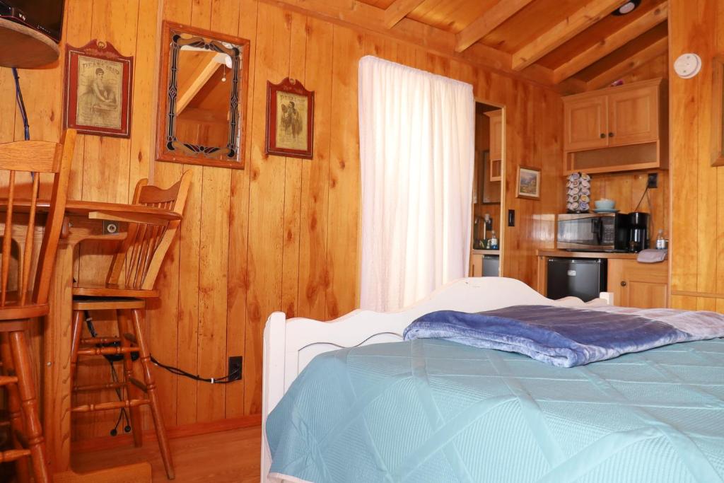 a bedroom with a bed and a kitchen with wooden walls at Stampede RV B&B in Tombstone