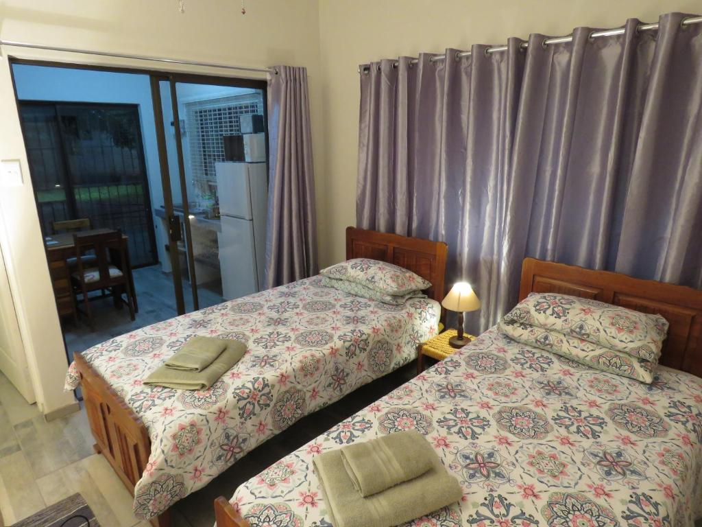 a bedroom with two beds and a door to a balcony at Parksig Self Catering in Musina