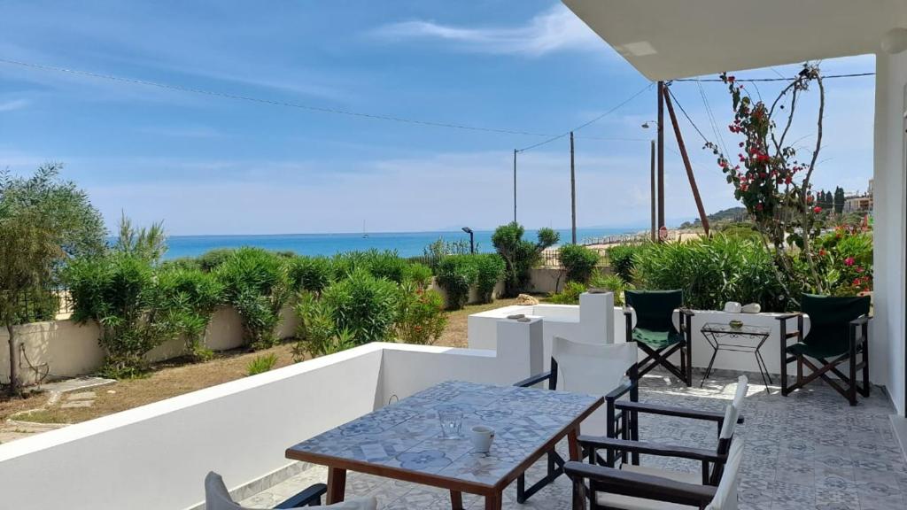 a patio with a table and chairs and the ocean at Beachfront Oleanders House in Skala in Skala Kefalonias