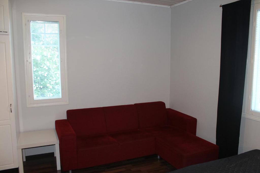 a red couch in a room with two windows at Oulunsalo Apartment in Oulunsalo