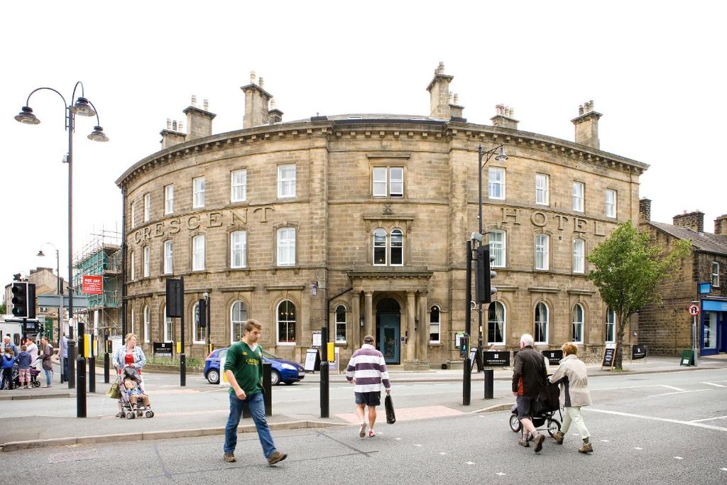 a group of people crossing a street in front of a building at Rooms by Bistrot Pierre at The Crescent Inn in Ilkley