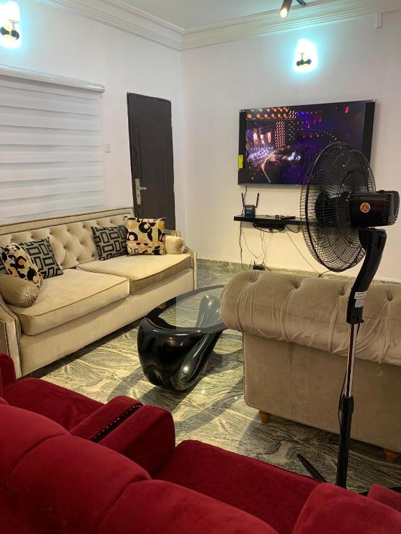 a living room with two couches and a fan at Jesam House in Suru Lere