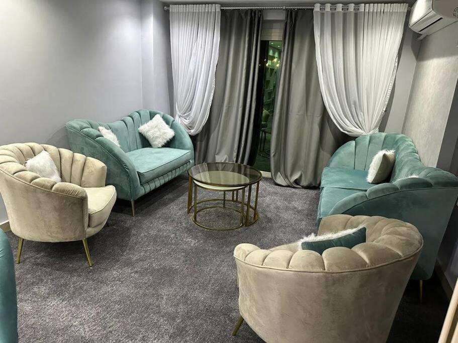 カイロにある3 bedroom apartment, Sheraton Al Matar, Nozhaのリビングルーム(青い椅子、テーブル付)