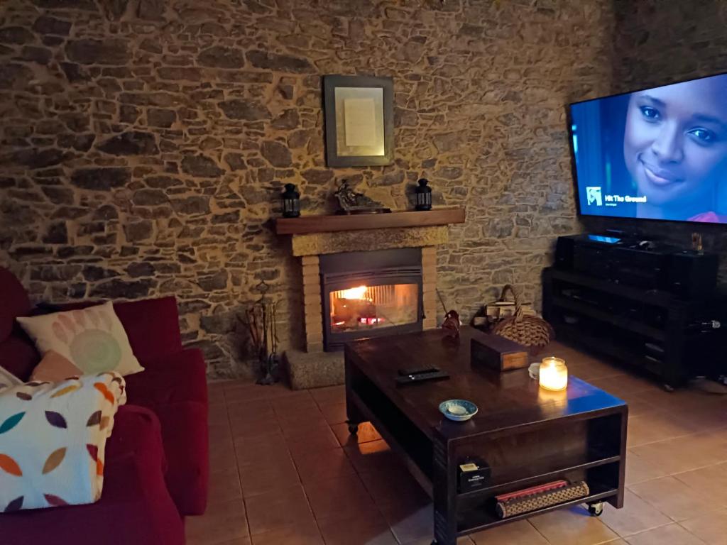 un salon avec une télévision et une cheminée dans l'établissement A Casa do Ferrador, à Vilar