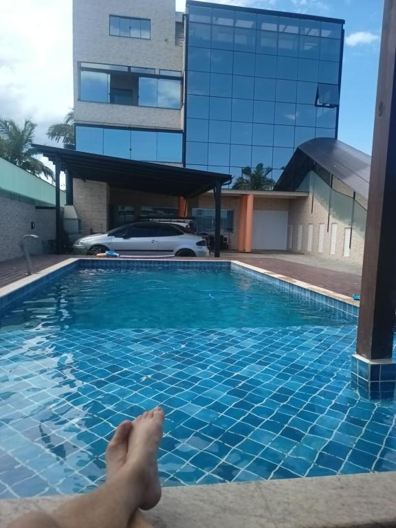 a person laying on the edge of a swimming pool at Apartamento completo 1 quarto in Palhoça