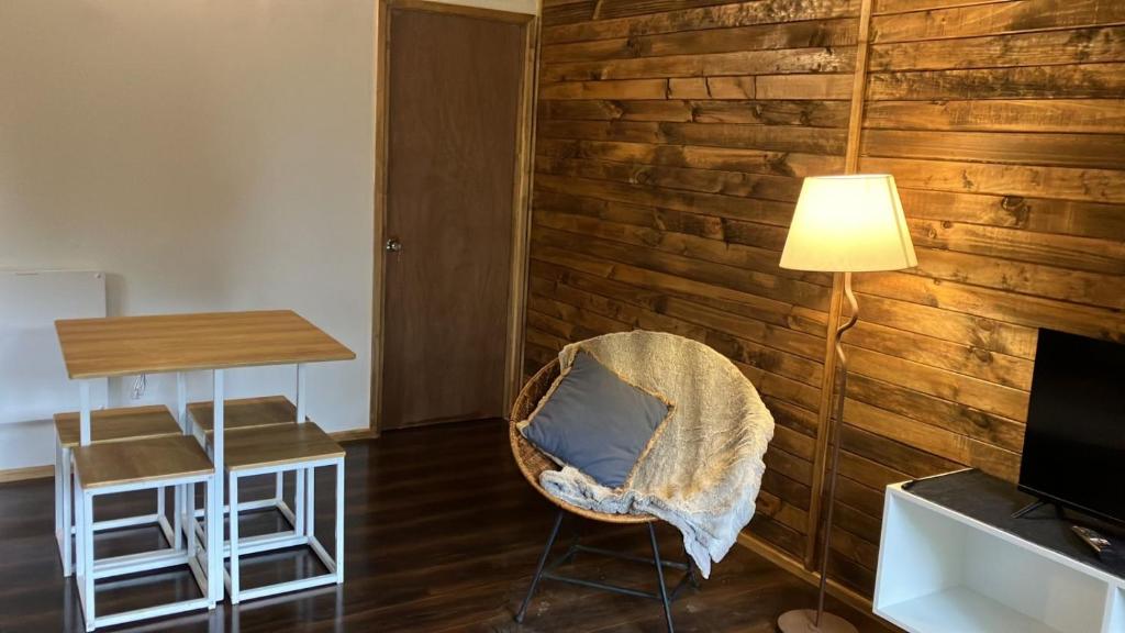 een kamer met een stoel, een tafel en een lamp bij Cay Cay lodge in Valdivia