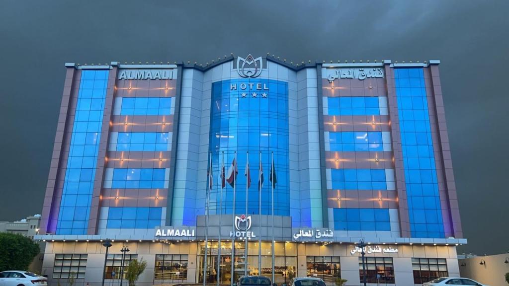 un grande edificio blu con macchine parcheggiate di fronte di Al Maali Hotel Jazan a Jazan