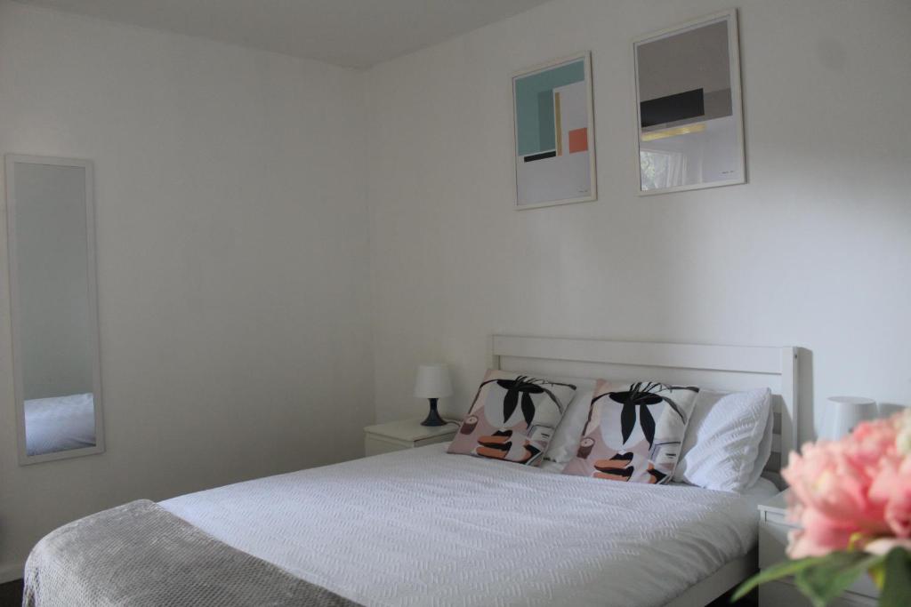 ein weißes Schlafzimmer mit einem Bett mit zwei Kissen in der Unterkunft The Yellow House in London