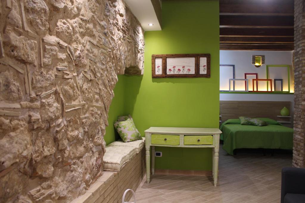 Habitación con pared de piedra, mesa y cama. en Guest House La Casetta, en Piazza Armerina