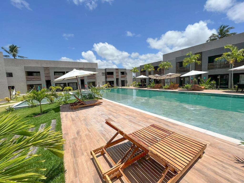 une piscine avec deux chaises et un bâtiment dans l'établissement Excelente condomínio com uma belíssima área de lazer próximo à praia do Patacho, à Porto de Pedras