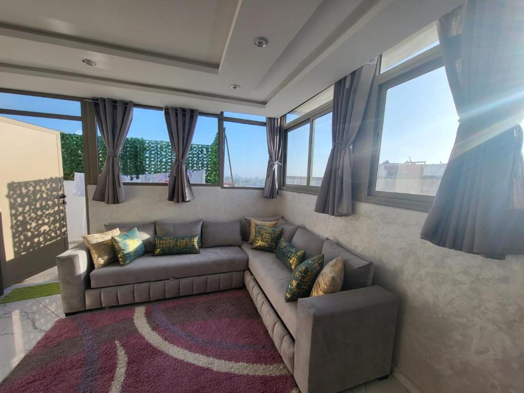 - un salon avec un canapé et quelques fenêtres dans l'établissement Modern Studio Just Steps from the Beach, à El Jadida