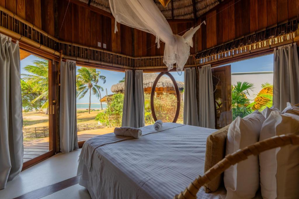 a bedroom with a bed with a view of the ocean at BAMBU BLU Lagoon Homes in Itarema