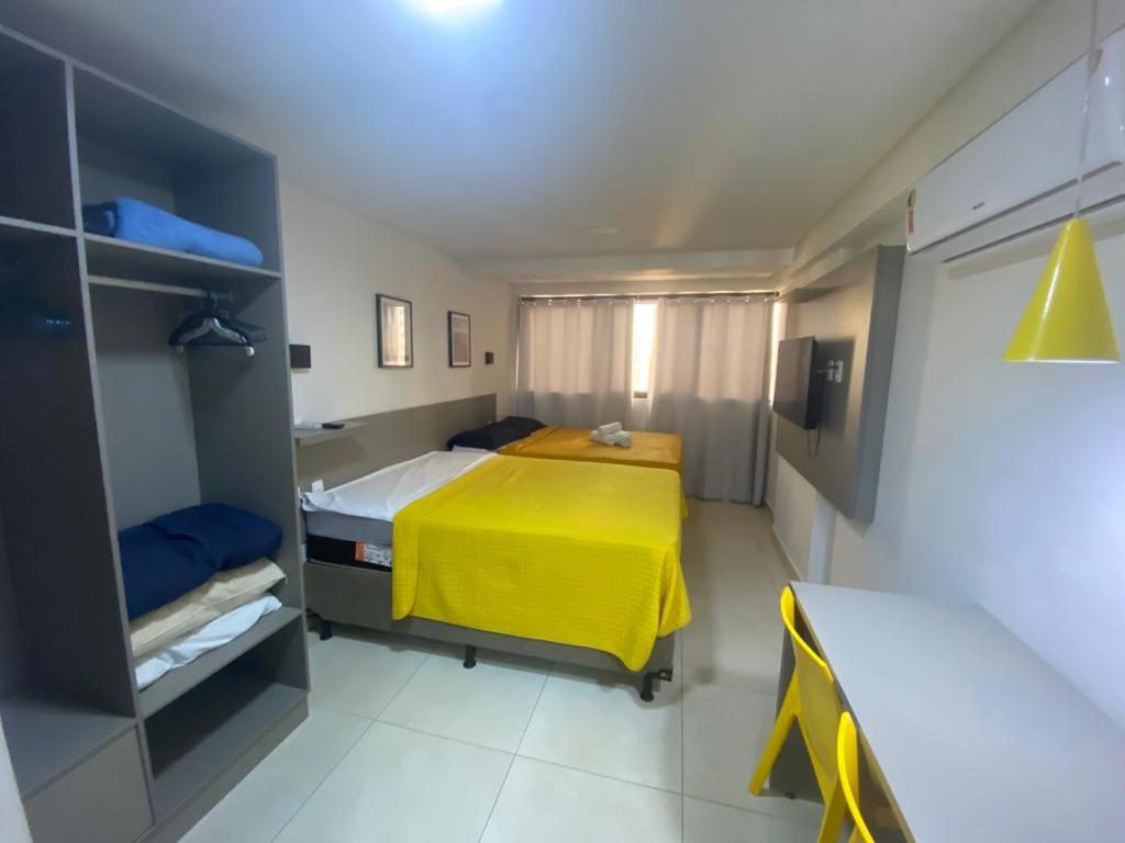 Un pequeño dormitorio con una manta amarilla en una cama en Manaíra Apart Hotel 1505, en João Pessoa
