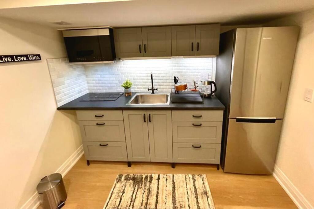 a small kitchen with a sink and a refrigerator at Cozy basement studio unit in Oakville