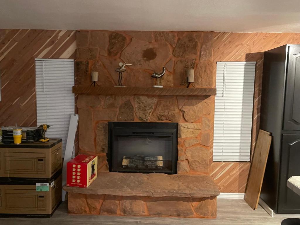 a living room with a stone fireplace with two windows at Crazy Horse - APT 1 in Kanab