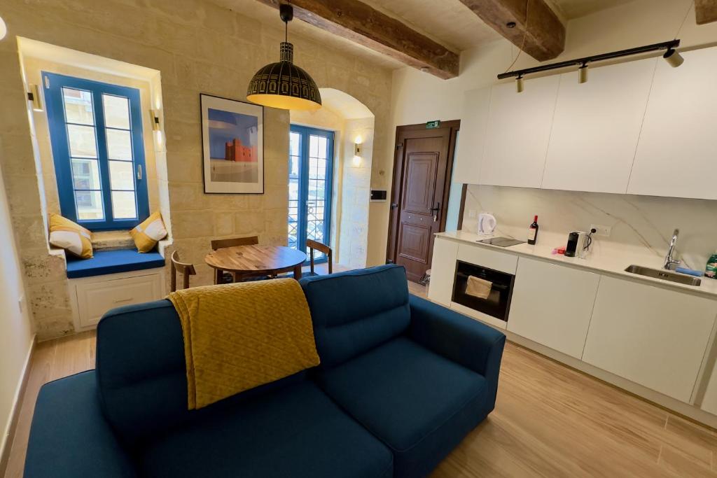 un soggiorno con un divano blu e una cucina di Valletta Dome Apartment a La Valletta
