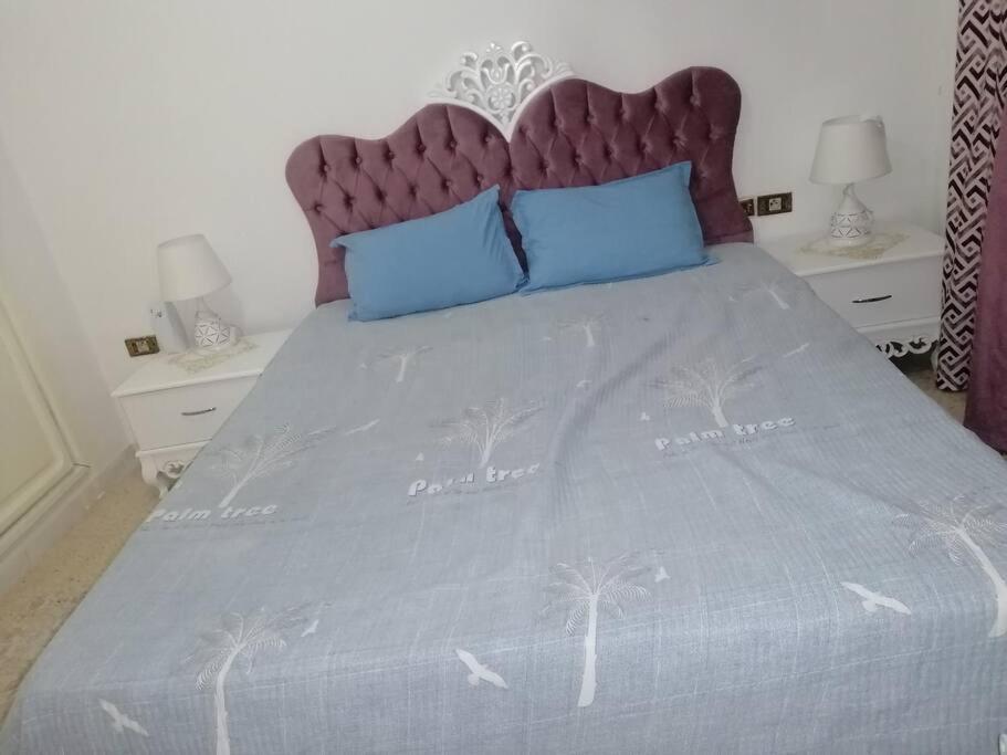 ein Bett mit einer lila Bettdecke mit Palmen darauf in der Unterkunft Superbe appartement en plein médina de Tunis in Tunis