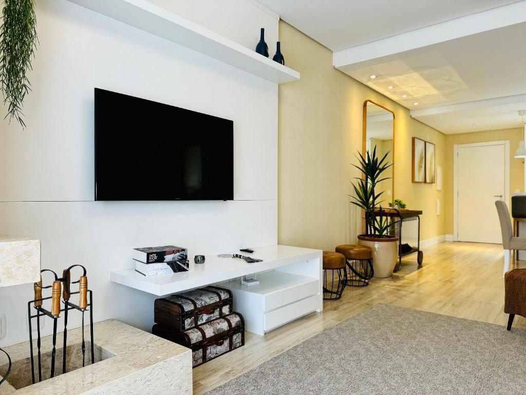 sala de estar con TV de pantalla plana en la pared en MRG Luxo e Tranquilidade Casa de Pedra 2D, en Gramado