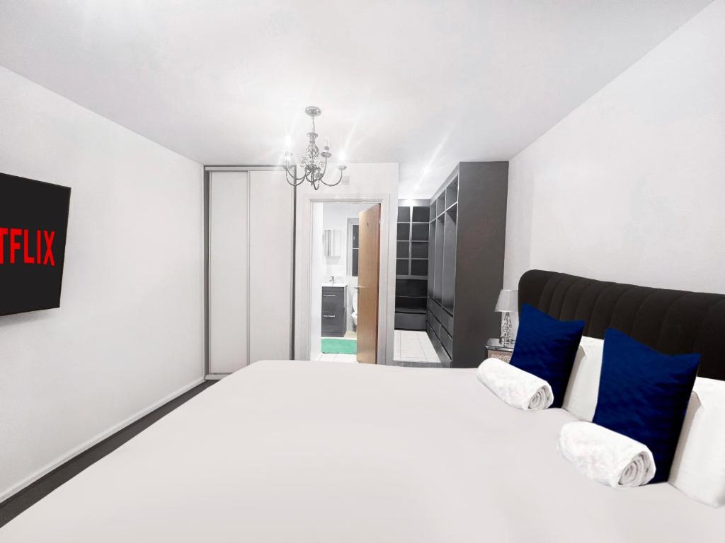 a white bedroom with a large bed with blue pillows at Private Rooms at Oxley Comfy House - Milton Keynes in Broughton