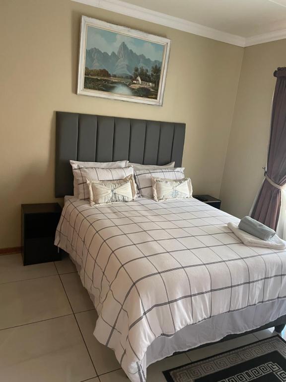 a bedroom with a large bed with a striped blanket at Azalea BnB in Kuruman