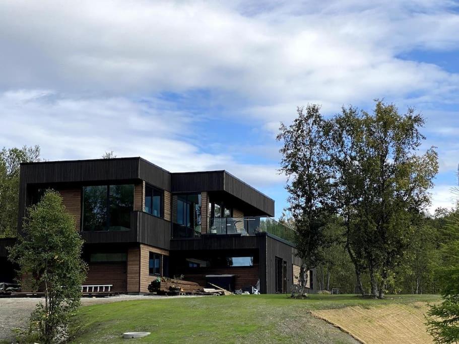een groot zwart huis op een grasveld bij Hjemmekoselig leilighet med nydelig utsikt in Tromsø
