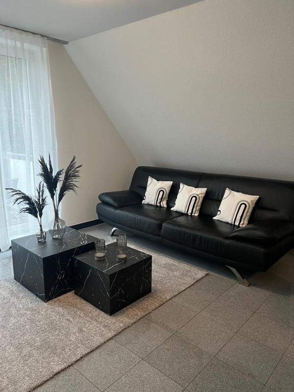 czarna kanapa w salonie z dwoma stołami w obiekcie Apartment by Harbali w mieście Schüttorf