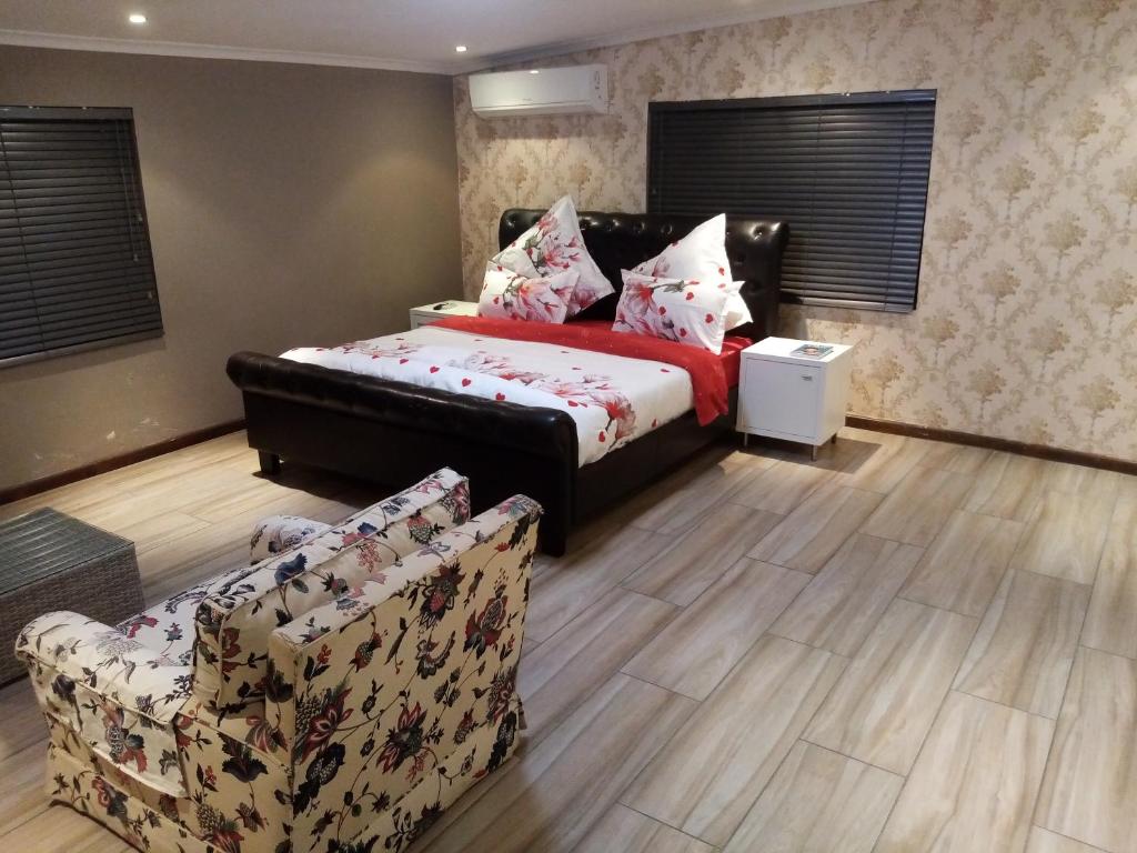a bedroom with a bed and a couch and chairs at Villa43guesthouse in Cape Town