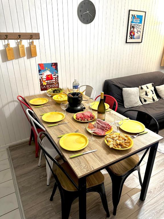 stolik z żółtymi talerzami i butelkę wina w obiekcie Appartement cosy Centre station de Super Besse pour 2 à 6 personnes w mieście Besse-et-Saint-Anastaise