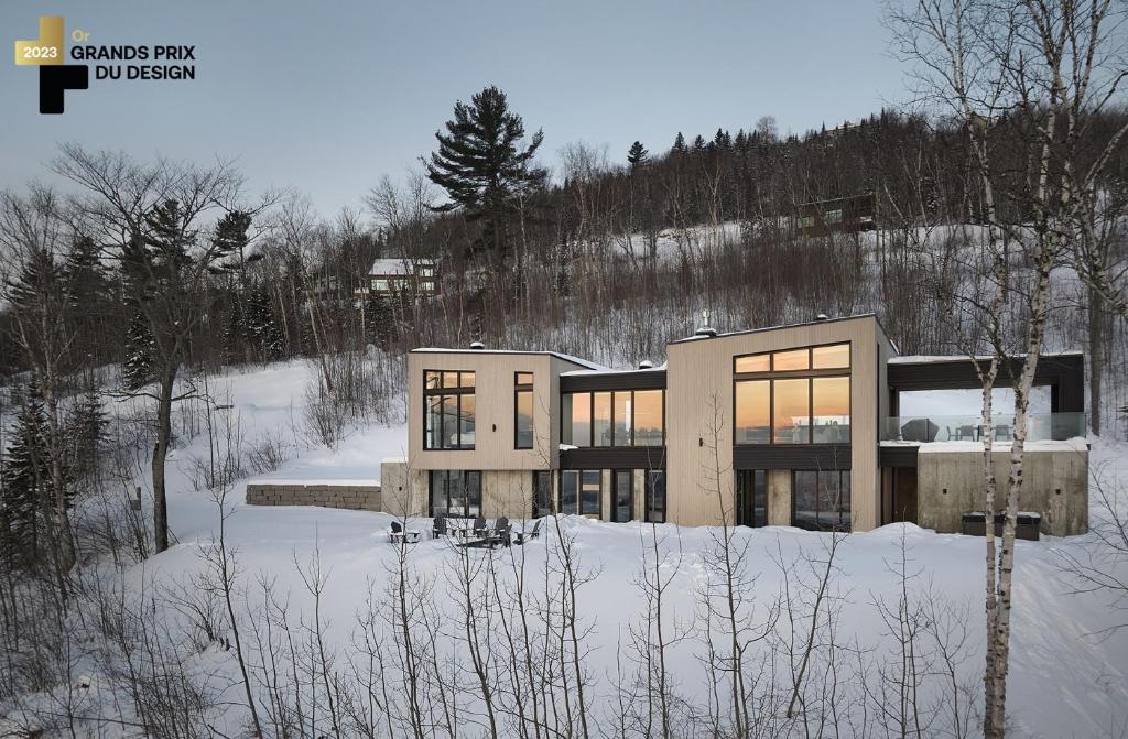 a house on a hill with snow on the ground at Panorama Charlevoix - Pool, Spa, Exceptional View in Les Éboulements