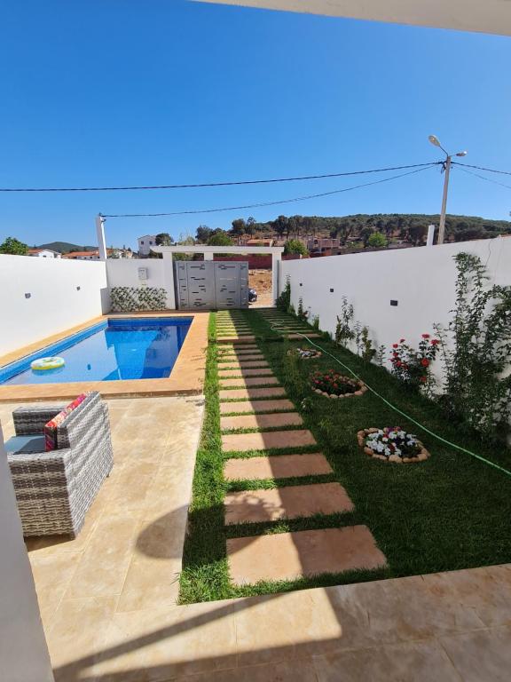 un patio trasero con césped y piscina en Villa de luxe, en Imouzzer Kandar