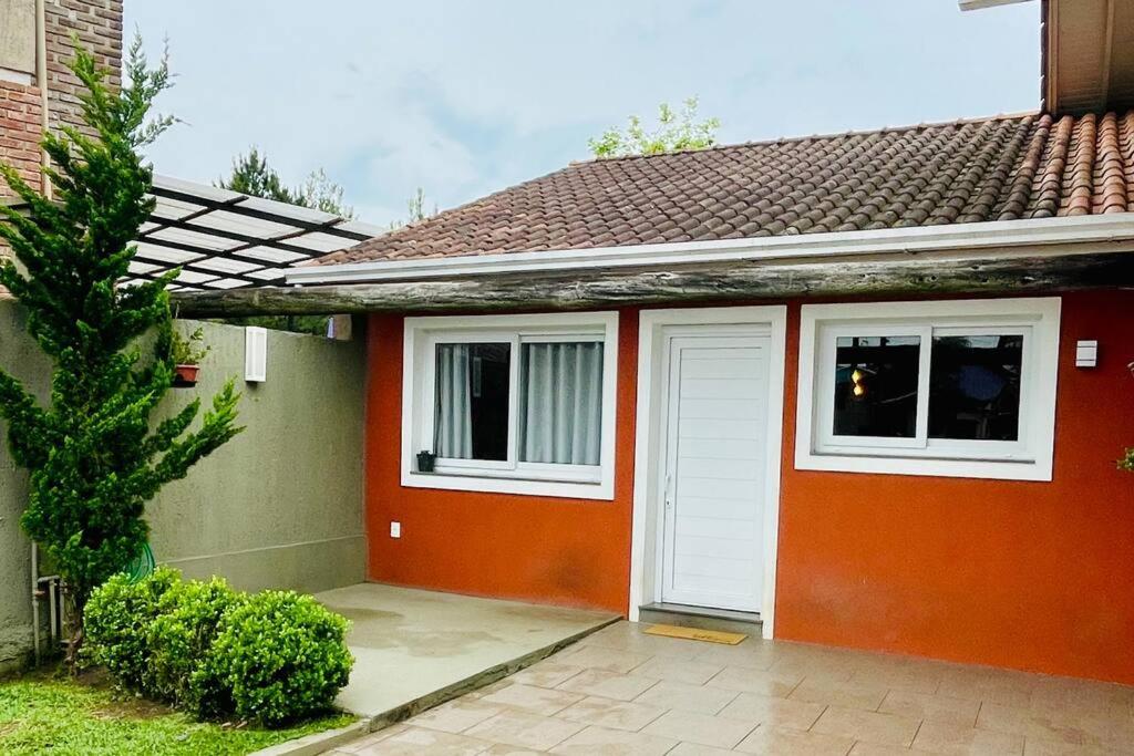 uma casa vermelha com uma porta branca e janelas em Casa aconchegante em Canela em Canela