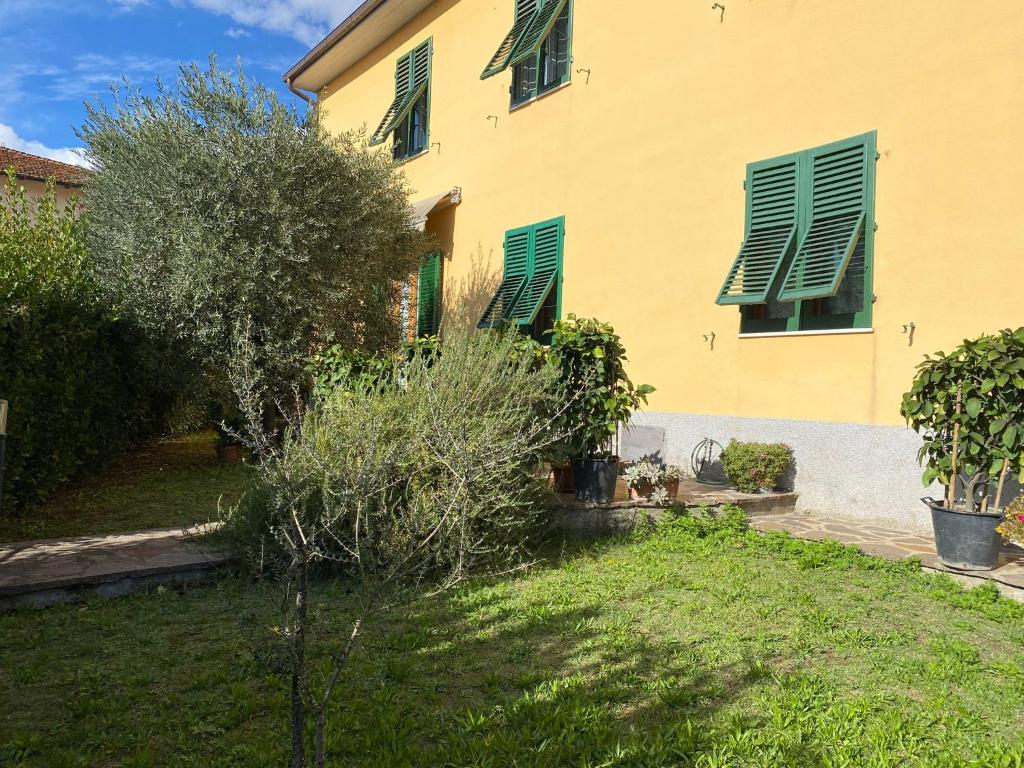 a yellow building with green shuttered windows and a yard at Le Siepi in Reggello