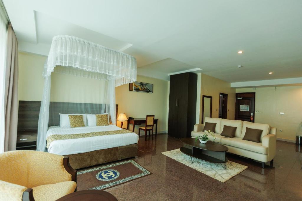 a bedroom with a bed and a couch and a table at Koki Hotel in Kampala