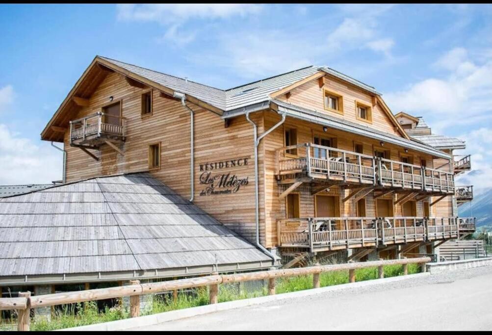 une grande maison en bois avec un toit en métal dans l'établissement T2 au pied des pistes de La Joue du Loup avec piscine et sauna, à Saint-Étienne-en-Dévoluy