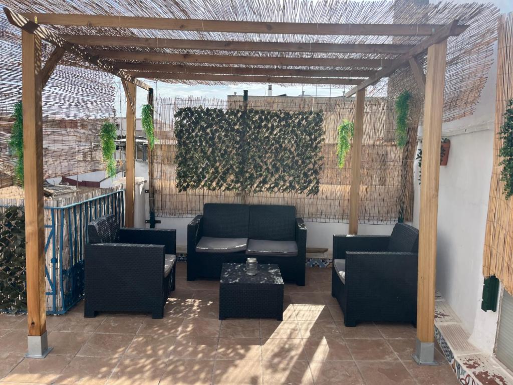 eine Pergola mit Sofas und einem Tisch auf der Terrasse in der Unterkunft Alzira bonita Ático E Plaza Mayor con gran terraza in Alzira
