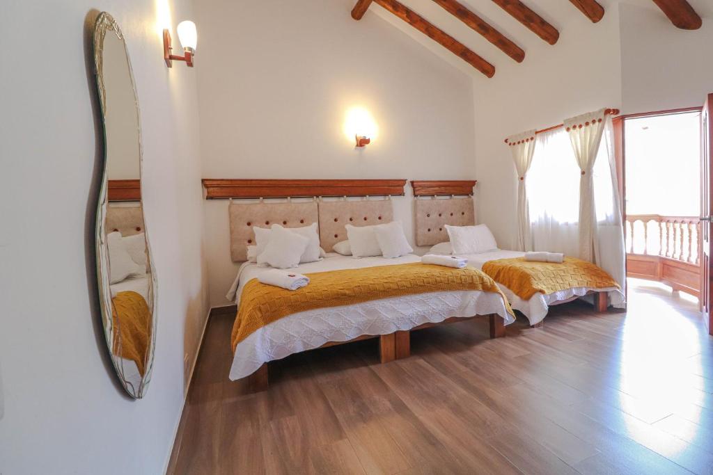 1 dormitorio con 2 camas y un espejo grande en Hotel las Palmas, en Villa de Leyva