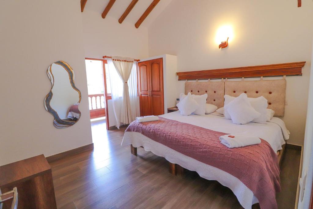 una camera da letto con un letto grande con una coperta rossa di Hotel las Palmas a Villa de Leyva