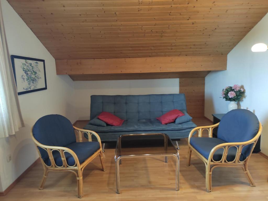 a living room with a blue couch and two chairs at FeWoIngrid in Zorneding