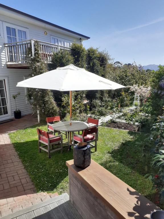 a table and chairs with an umbrella in a yard at Magnolia Cottage in Christchurch