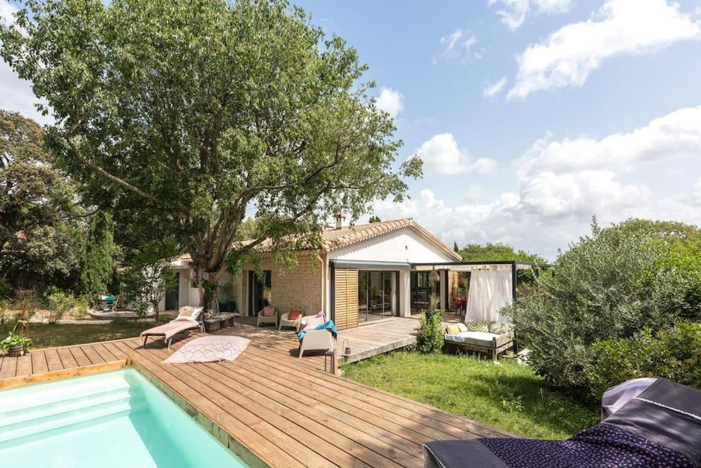 a backyard with a wooden deck and a swimming pool at La Coursive : belle maison de standing avec piscine in Montpellier