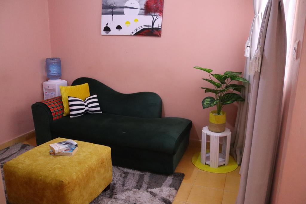 una sala de estar con un sofá verde y una planta en Cozy 1 bedroom apartment in Claycity, Kasarani, en Nairobi