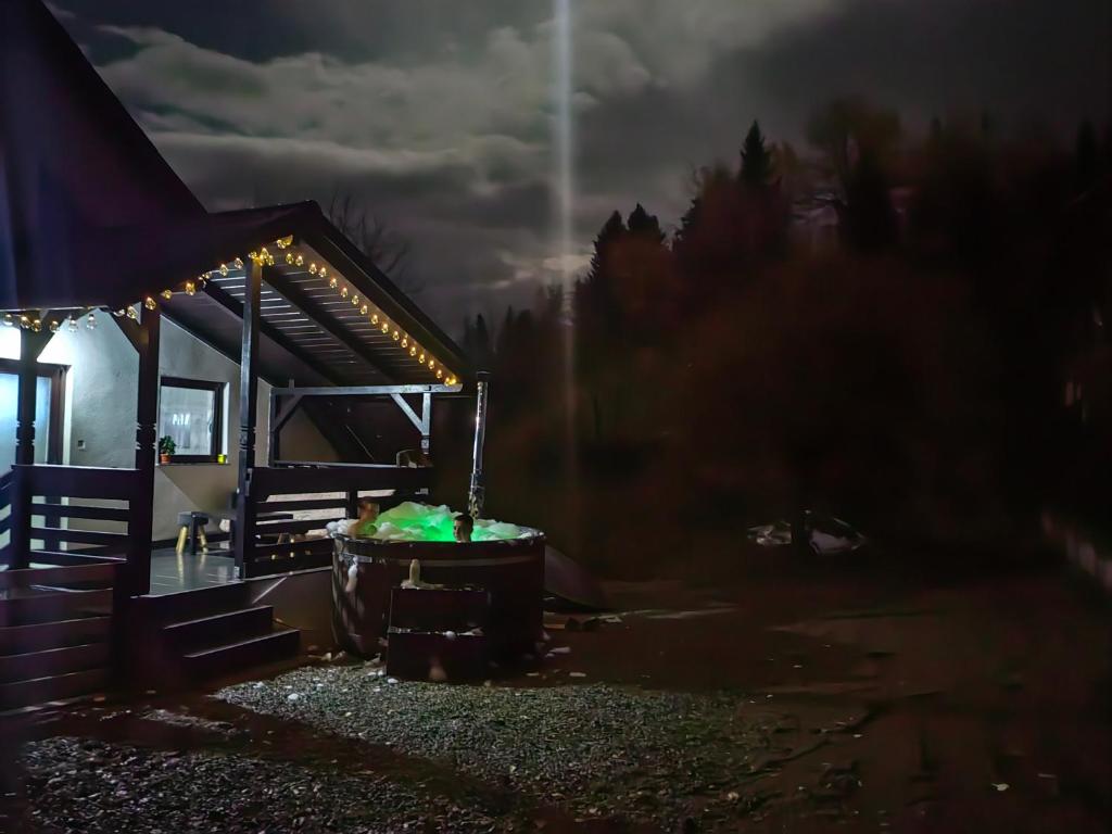een nachtzicht op een hut met een hot tub bij Alissa House in Borsa