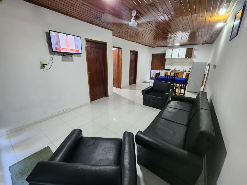 Il comprend un salon doté d'un mobilier en cuir noir et d'une télévision à écran plat. dans l'établissement Casa amoblada en Villarrica - Py, à Villarrica